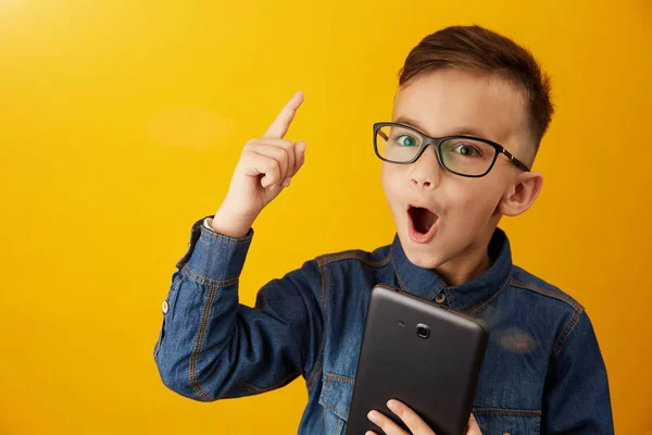 Sarı bir arka plan üzerinde elinde bir tablet ile çocuk — Stok fotoğraf