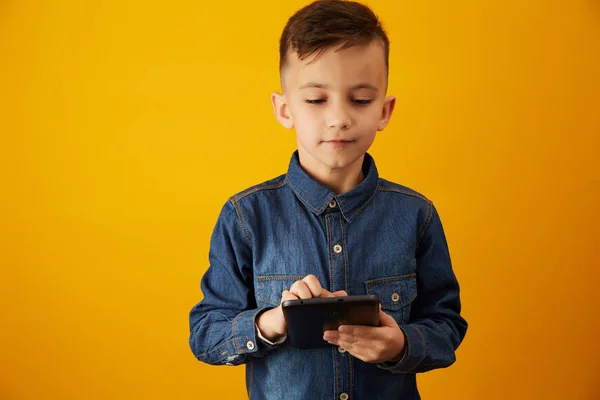 Мальчик держит планшет на желтом фоне — стоковое фото