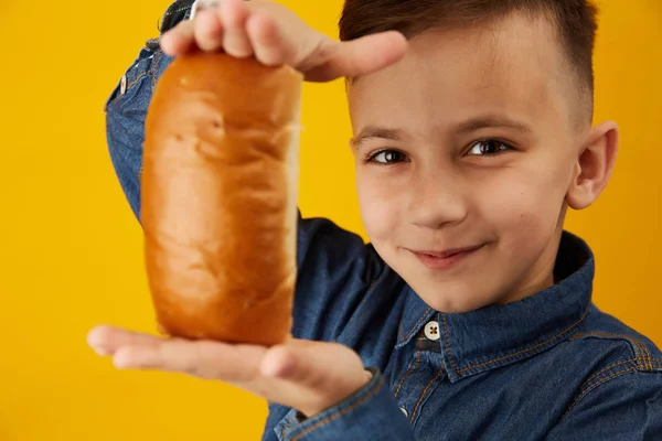 Happy Boy comer grande sanduíche ou cachorro-quente isolado fundo amarelo — Fotografia de Stock