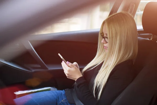 Junge Geschäftsfrau verschickt während des Autofahrens eine SMS — Stockfoto