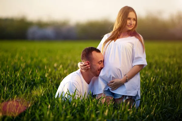 Pregnant couple in the green grass — Stock Photo, Image