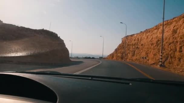 Driving a car on Red Rock Canyon Road in the Red Rock Canyon National Conservation Area in Nevada. The late afternoon sun creates a lens flare over the roadway. — Stock Video