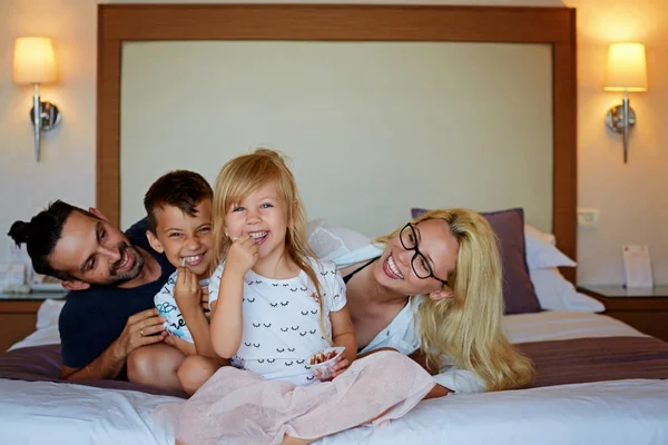 Familia feliz divirtiéndose juntos acostados en una cama — Foto de Stock