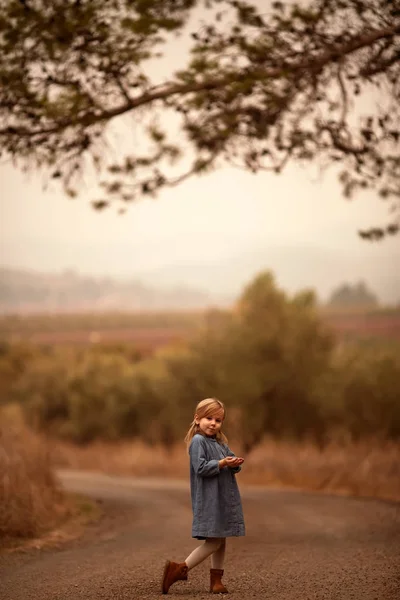 Chica caminando a lo largo de la carretera en un campo solo — Foto de Stock