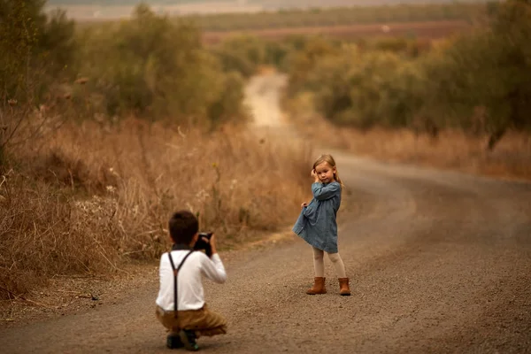 Chlapce fotograf pořídí dítě v parku v poli na silnici — Stock fotografie