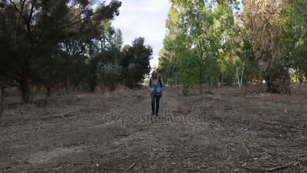 Amazing young woman with a vintage camera taking on her backpack and starting walking, than taking photos of the forest around her. Forest in sunlight. Outside — Stock Video