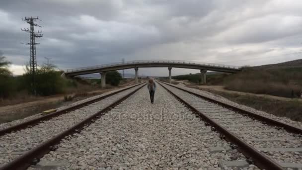 Jonge vrouw lopen op de rails van de spoorweg — Stockvideo