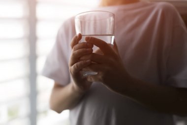 Genç adam bir bardak su, atış closeup ile tutarak