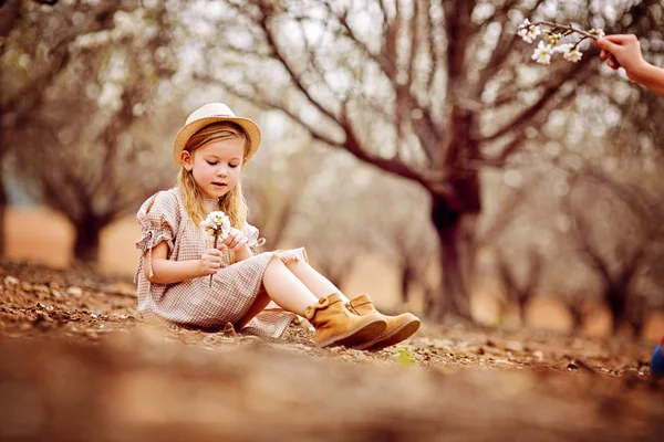 Little girl blonde with long hair in dress sitting on the road — Stock Photo, Image