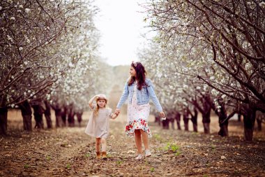 İki küçük kız kardeş beyaz birbirlerine elele ve parkta açık havada dans giymiş