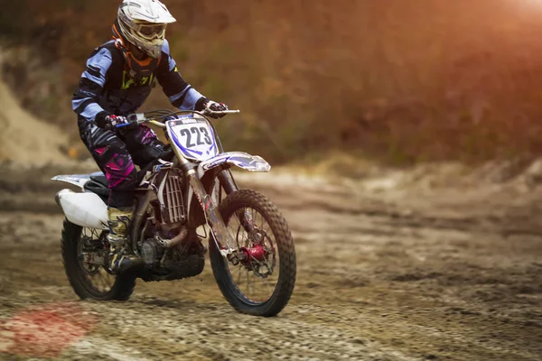 Hombre montando moto naranja vivo rápido en el bosque. Fondo borroso en movimiento — Foto de Stock