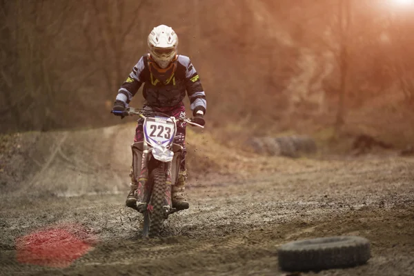 Motocross jinete de competición en un camino de tierra en el bosque —  Fotos de Stock