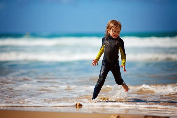 해변에서 파도 함께 놀이 실행 하는 어린 소녀 — 스톡 사진