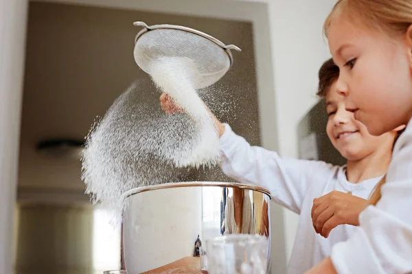 Веселые брат и сестра в белых футболках на кухне подготовить тесто . — стоковое фото