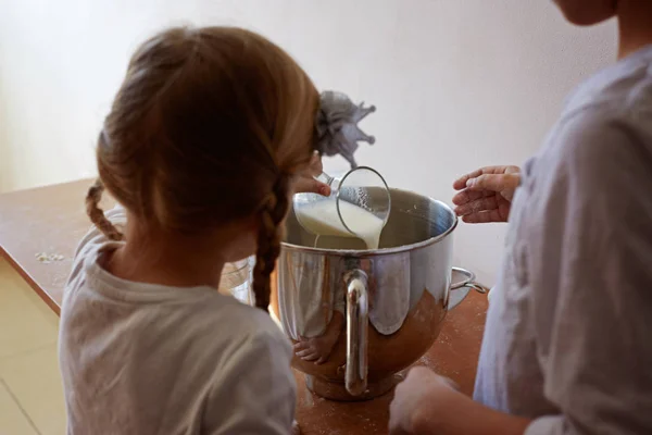 Маленькая девочка завтракает: наливая молоко в миску — стоковое фото