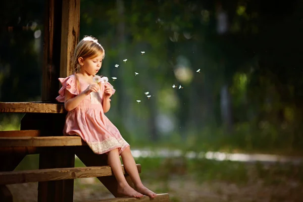 Schönes Kind mit Löwenzahnblüte im Frühlingspark. Glückliches Kind, das Spaß im Freien hat. — Stockfoto