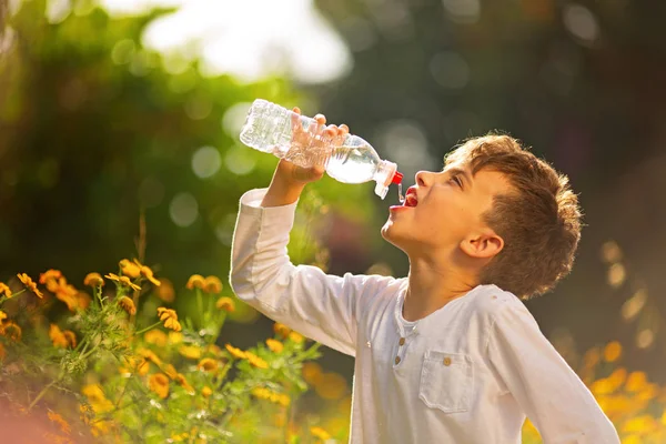 夏の暑い日に屋外の瓶を飲んで透明なプラスチックから純粋な水道水を飲む少年のクローズ アップ — ストック写真