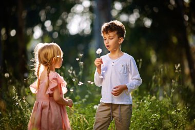 küçük erkek ve kız darbe dandelions, Bahar doğa oyunda