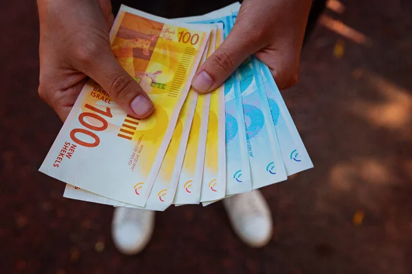 Woman's two hands holding a fan of money of Israeli New Shekels — Stock Photo, Image