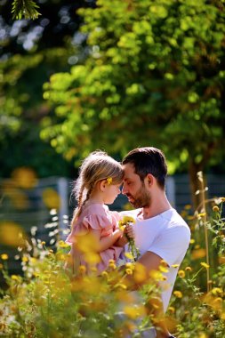 Aile zamanı. Babasının küçük kızı pembe elbisenin içinde tutar. Onu yanağından öptü. Bahar yürüyüşte