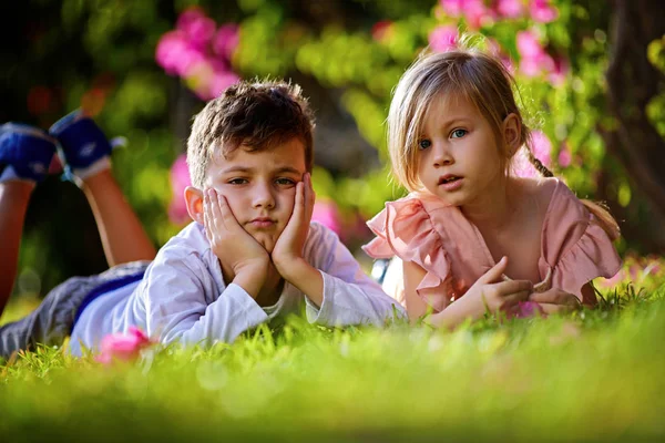 Meisje en jongen liggend op de groene weide — Stockfoto