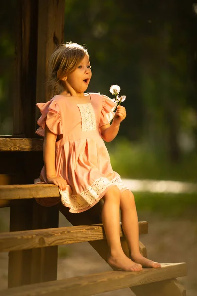 春の公園でタンポポの花を持つ美しい子供。楽しいアウトドアをしている幸せな子供. — ストック写真