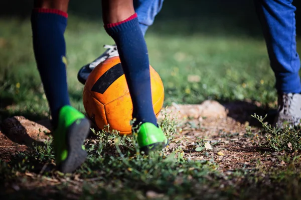Крупним планом маленька хлопчисько-нога грає у футбол на футбольному полі. — стокове фото