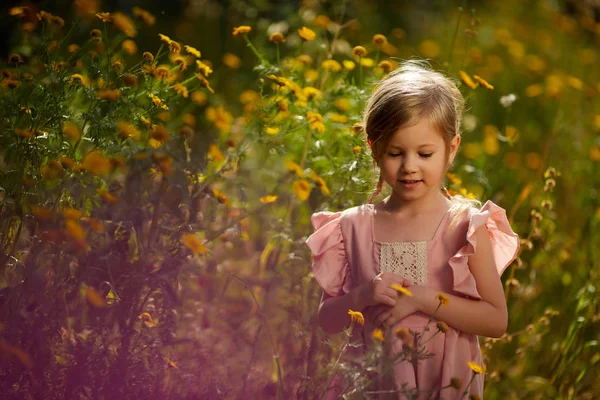 Småbarn flicka som leker i påsklilja fält. Barn Trädgårdsskötsel. Barn plockar blommor i trädgården. Barn som arbetar i trädgården. Barn att ta hand om växter. Första våren blommar. Påskägget — Stockfoto