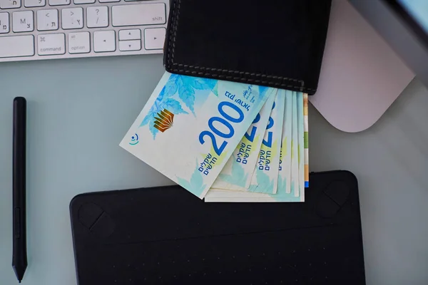 200 shekels en un bolso de cuero en una mesa de vidrio de trabajo . — Foto de Stock