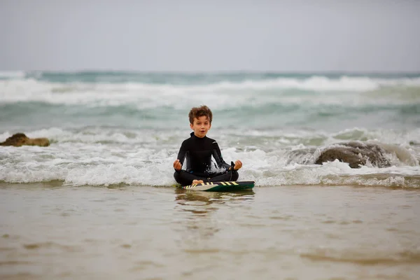 Мальчик медитирует на пляже у моря в солнечном свете . — стоковое фото