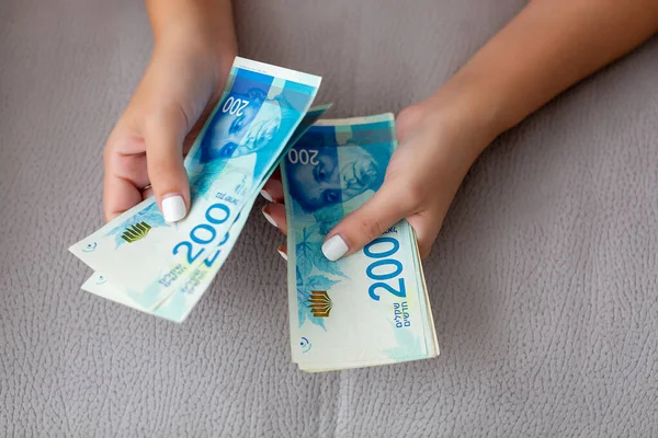 Sluiten van een meisje dat Israëlisch geld telt. Het tellen van 200 Israëlische shekel rekeningen close-up op grote hoeveelheid geld — Stockfoto