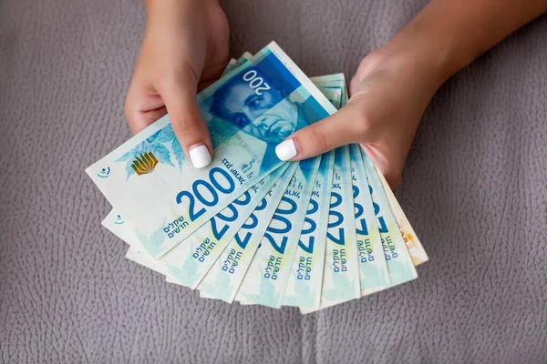 Mulheres duas mãos segurando um fã de dinheiro de New Shekels israelenses, o novo 200 shekel — Fotografia de Stock