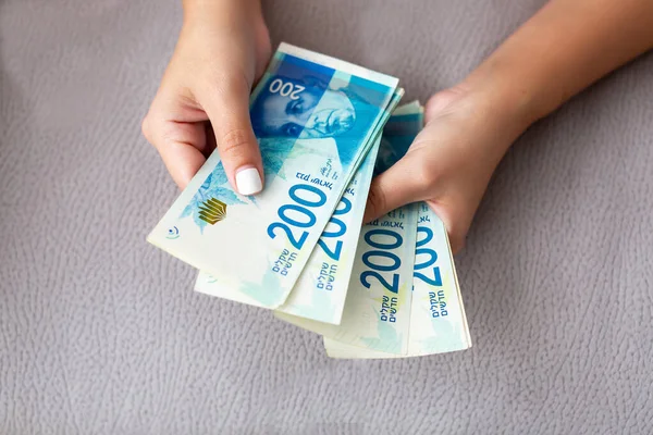 Fechar de uma menina contando dinheiro israelense. Contando 200 contas shekel israelenses - close-up em grande quantidade de dinheiro . — Fotografia de Stock