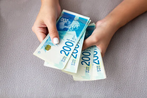 Närbild av en flicka som räknar israeliska pengar. Räkna 200 israeliska shekel räkningar - nära på stora summor pengar. — Stockfoto