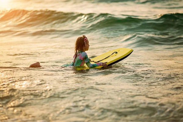 Bebé niña joven surfista paseo en tabla de surf con diversión en las olas del mar. Estilo de vida familiar activo —  Fotos de Stock