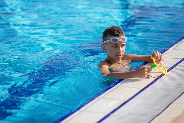 Kind beim Sport und Schwimmen unter Wasser im Pool vor blauem Hintergrund mit Spielzeug in den Händen — Stockfoto