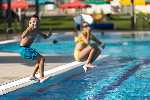 Весёлые дети прыгают в бассейн, концепция путешествий и летних каникул — стоковое фото