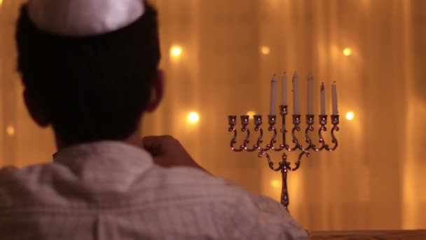 Rückansicht Jüdischer Junge zündet fünfte Menorah-Kerze während des jüdischen Festes Chanukka an — Stockvideo
