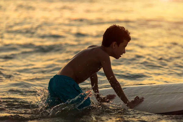 Ein müder Kerl mit Surfbrett im Badeanzug, um Rutschen auf den Wellen zu lernen — Stockfoto