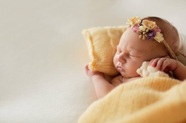 Yeni doğmuş bebek sarı yastıkta kafasında bir çember ile