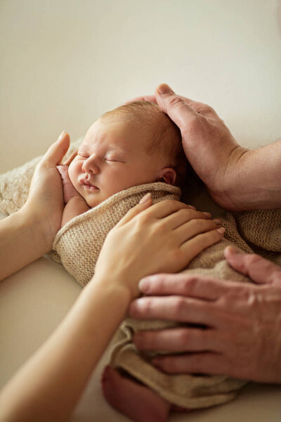 Милая новорожденная девочка, лежащая на руках отца и матери, дома
