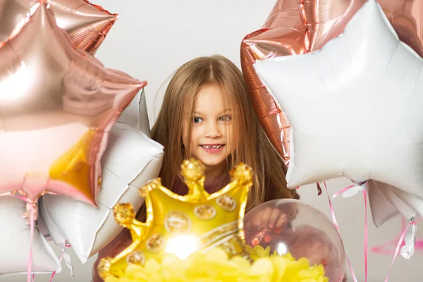 Το κοριτσάκι παίζει με μπαλόνια. Πορτρέτο του μικρού κοριτσιού που παίζει με αερόστατα. Ευτυχισμένο κοριτσάκι κρατώντας πολύχρωμα μπαλόνια. Χαμογελαστό παιδί. — Φωτογραφία Αρχείου