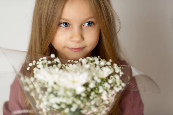 Skönhet ung blond flicka med en bukett av vilda blommor med väderbitna läppar — Stockfoto