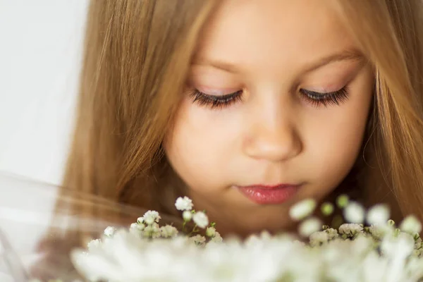 Närbild vacker liten blond flicka med en bukett av vilda blommor med väderbitna läppar — Stockfoto