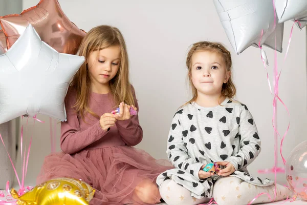 Two blonde little sisters play sitting on the floor in a photo studio — ストック写真