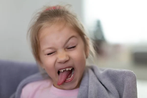 Közelkép portré vicces mosolygós kislány nyelv ki, és anélkül, hogy egy elülső fog — Stock Fotó