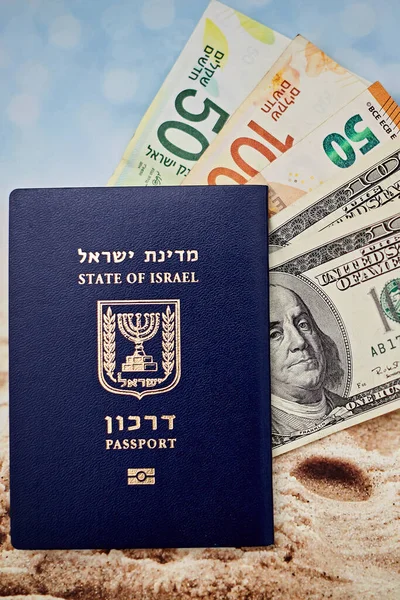 Ciudadano israelí pasaporte internacional billetes de cien dólares euros y shekels sobre arena y fondo marino —  Fotos de Stock