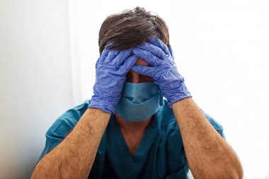Üzgün ve hayal kırıklığına uğramış bir doktor yüzünü çaresizce hareketlerle kapatır.