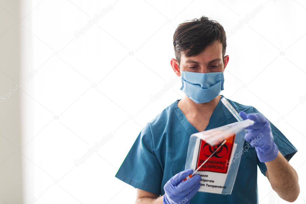 Medical healthcare technologist holding COVID-19 swab collection kit, wearing white protective suit mask and gloves, test tube for taking OP NP patient specimen sample, PCR DNA antigen testing