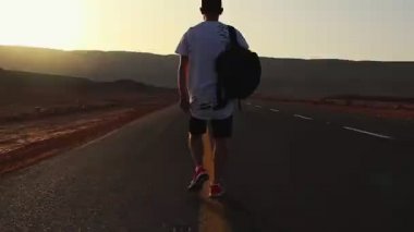 Yalnız Yakışıklı Adam Yürüyüşü ve Eğlencesi. Kendine güvenen adam gün doğumunda yolda yürüyor. Adam çölde yürüyor..
